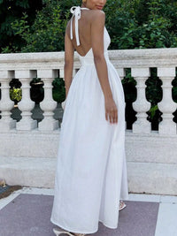 Woman wearing a white dress with a backless design, standing outdoors.