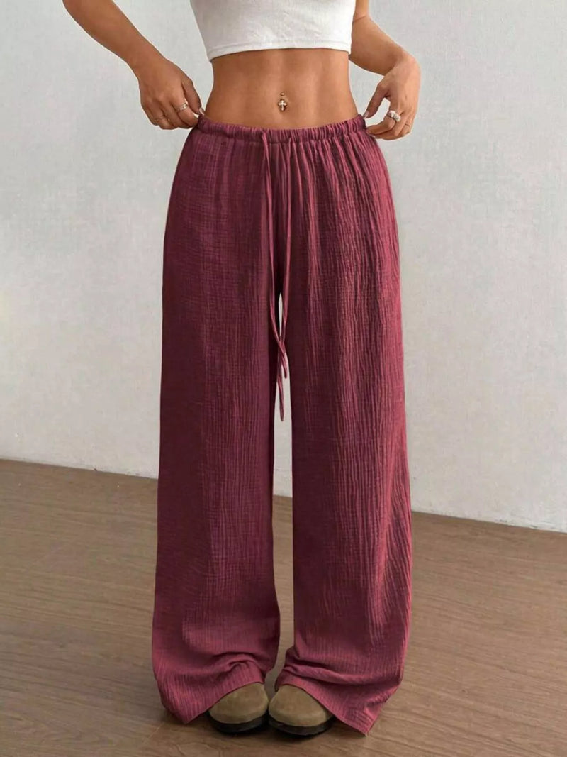 Person wearing maroon wide-leg pants against a plain background