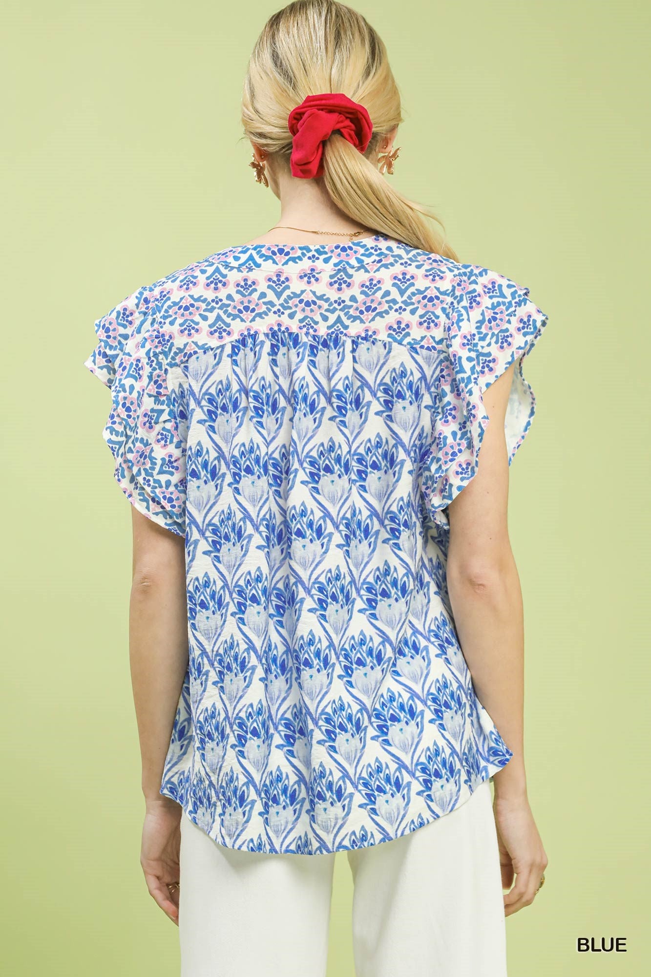 Woman wearing a blue and white floral patterned top on a light green background