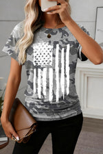 Person wearing a gray camouflage t-shirt with an American flag design, holding a phone.