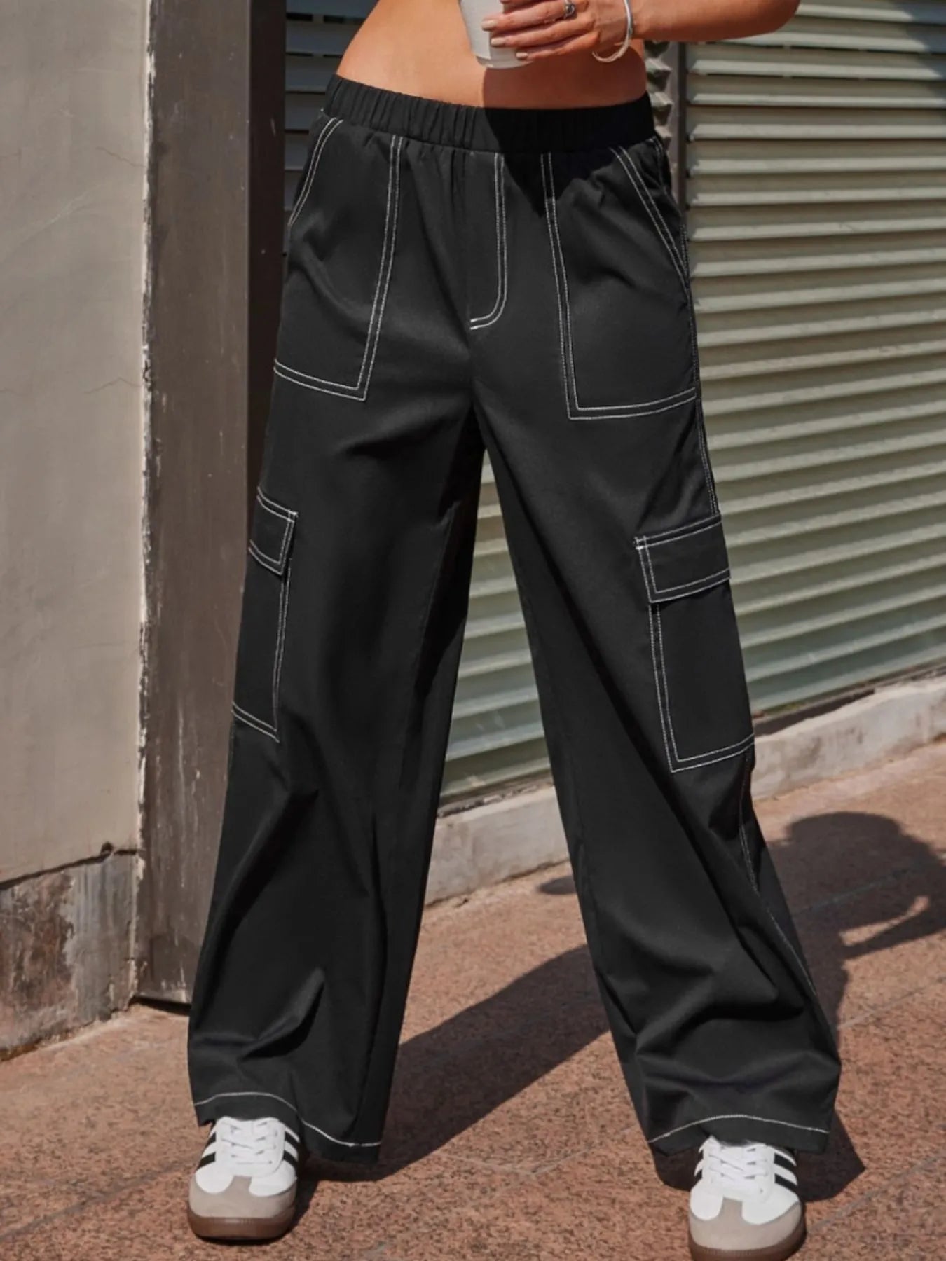 Person wearing black cargo pants standing against a metal shutter.