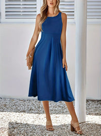 Woman wearing a blue dress standing outdoors with a neutral background