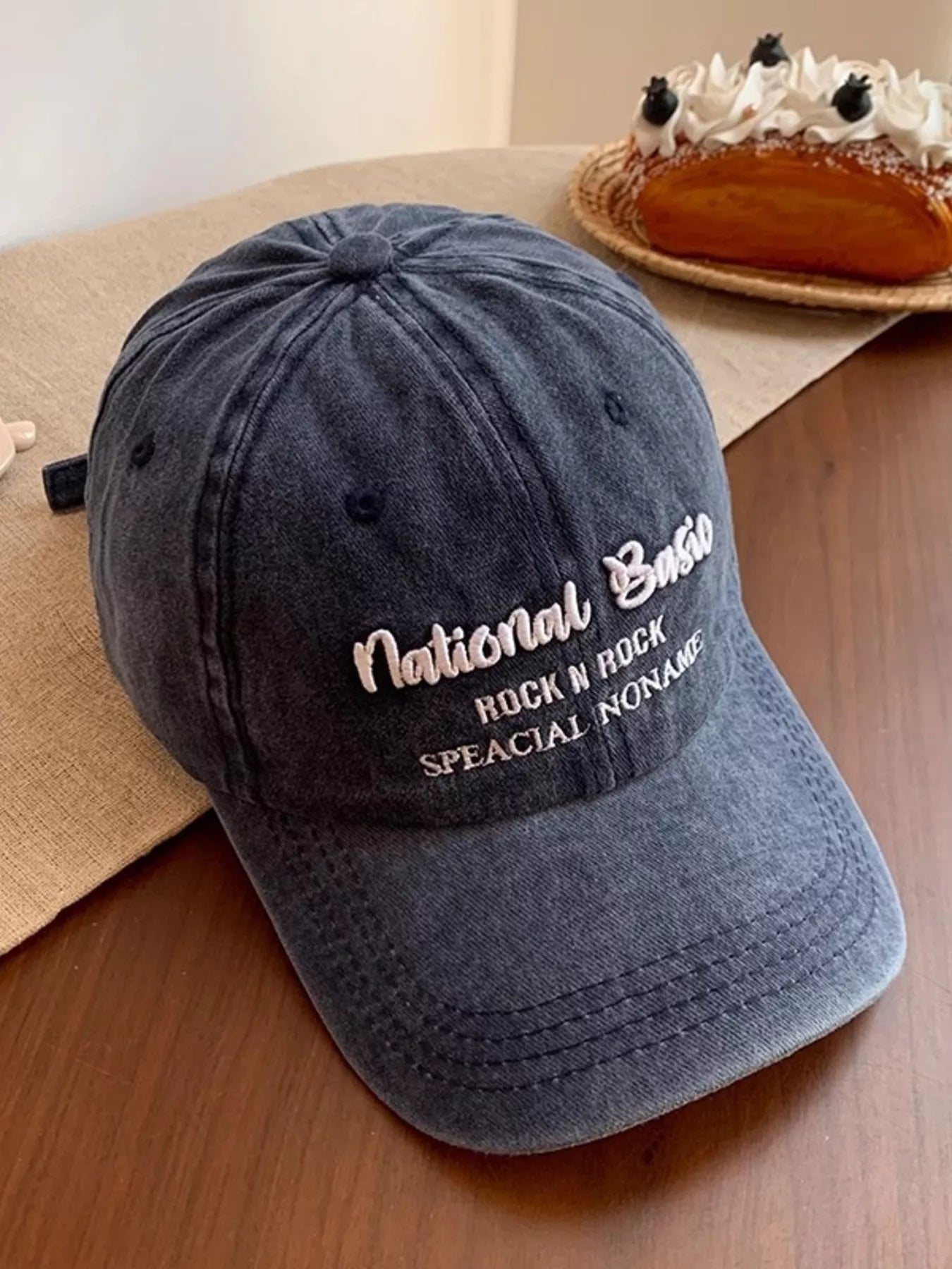 Blue cap with text on a wooden surface with a dessert in the background