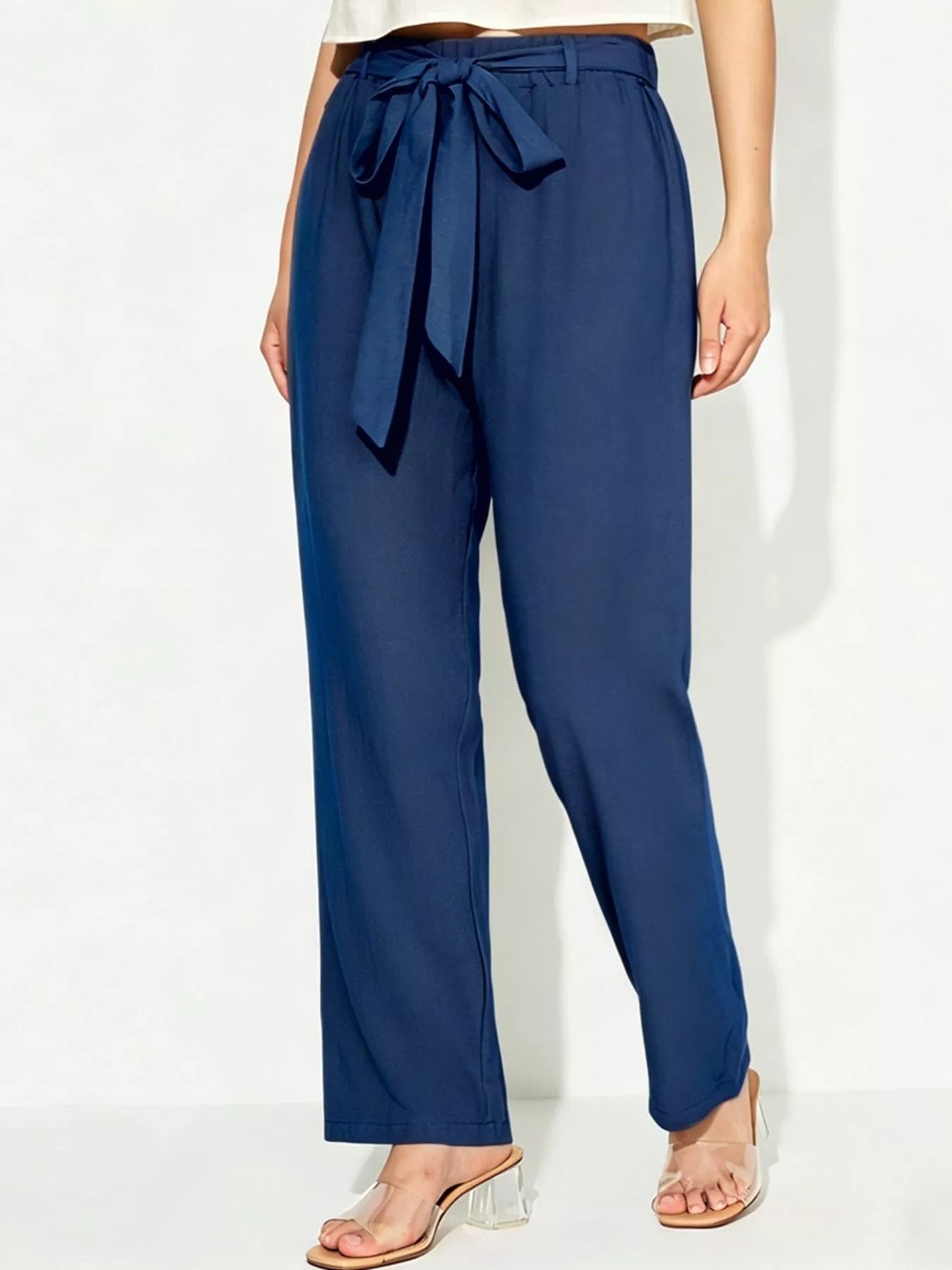 Navy blue pants with a tie waist on a white background