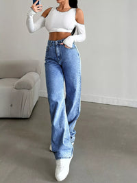 Person wearing a white crop top and blue jeans in a minimalistic room.