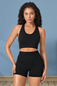 Woman wearing a black sports bra and shorts set against a blue background