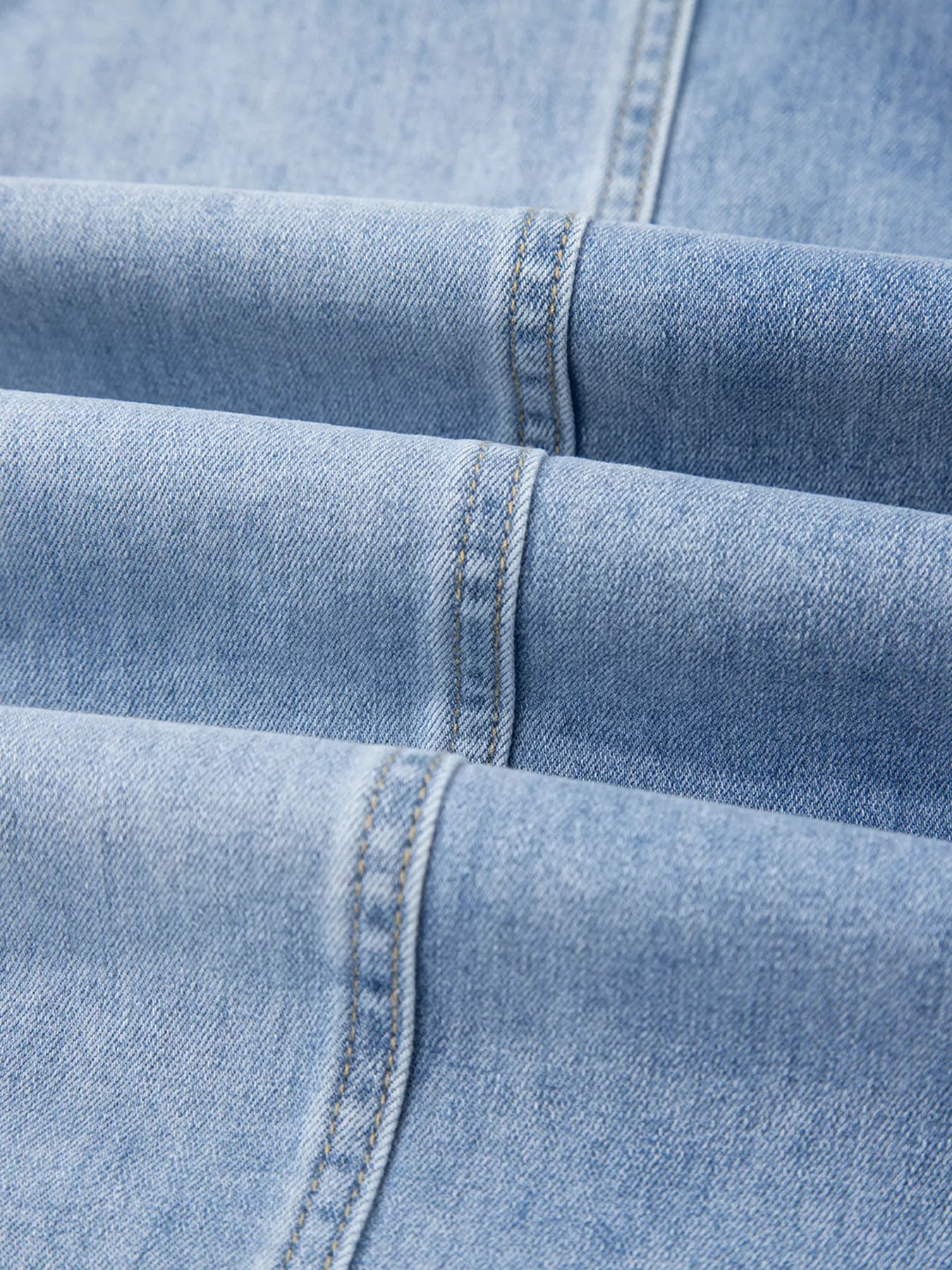 Close-up of light blue denim fabric with stitching details