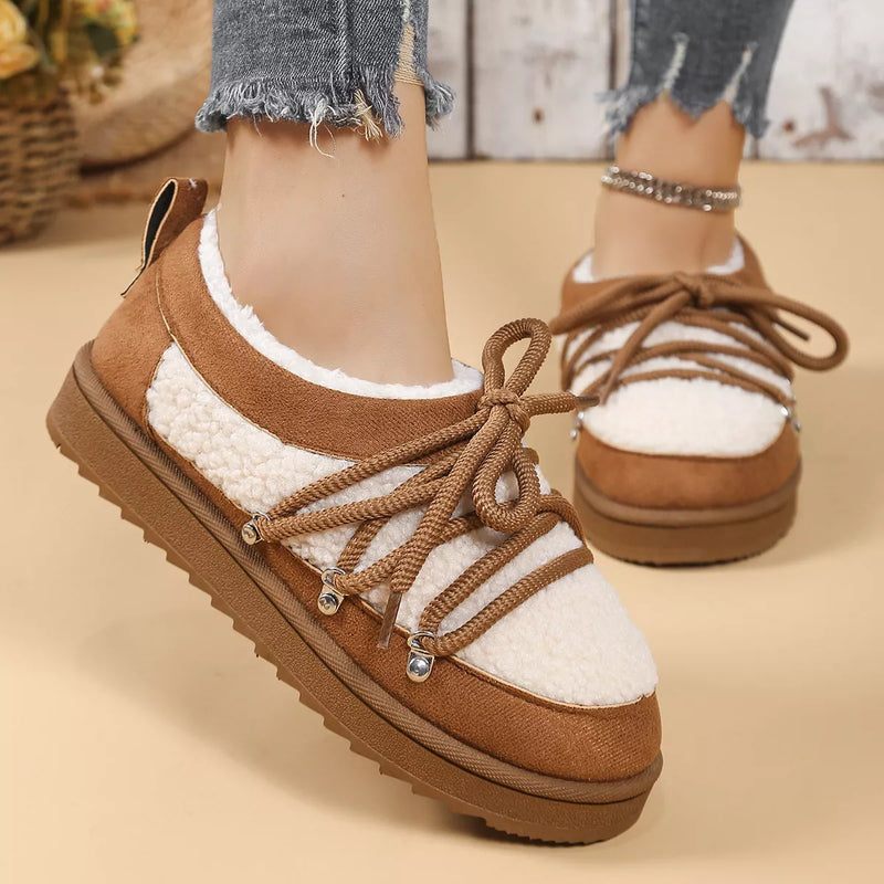Brown and white winter shoes with fur lining worn by a person on a beige background