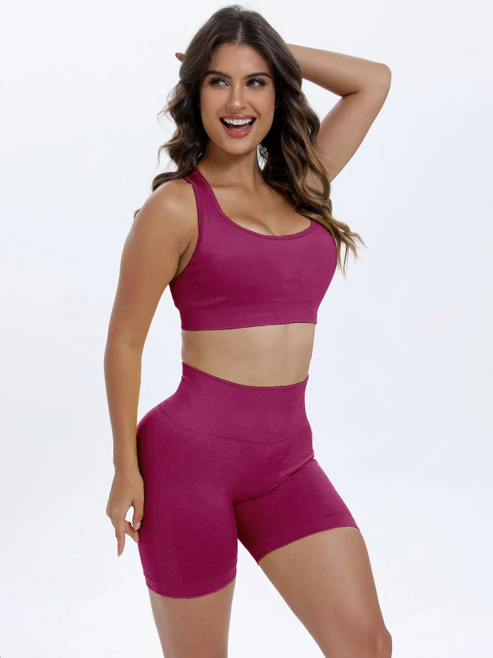 Woman wearing a pink sports bra and shorts on a white background