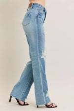 Light blue jeans with a slight distressed look worn by a person on a beige background