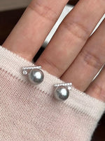 Pearl earrings on a hand with a soft background