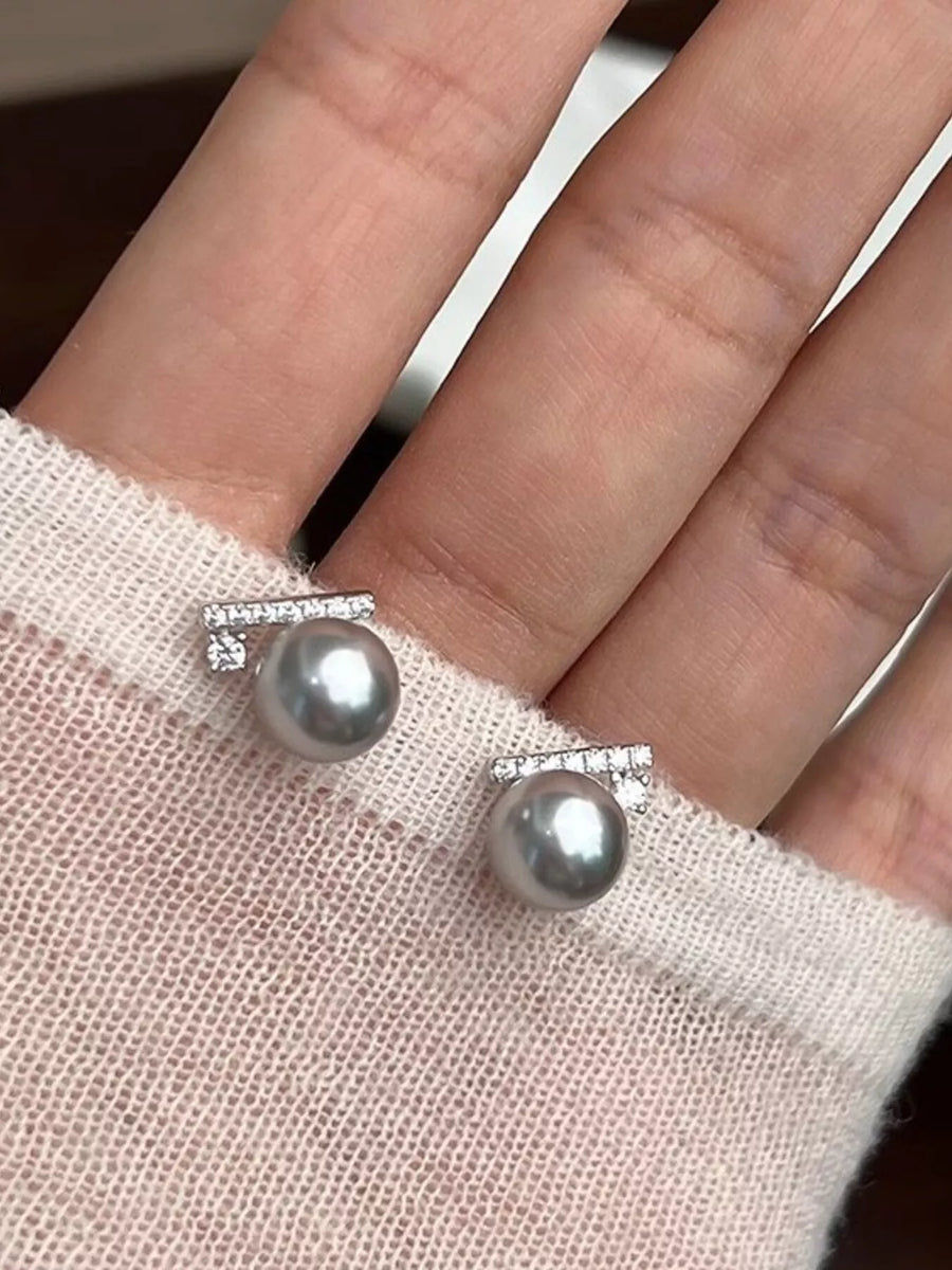 Pearl earrings on a hand with a soft background