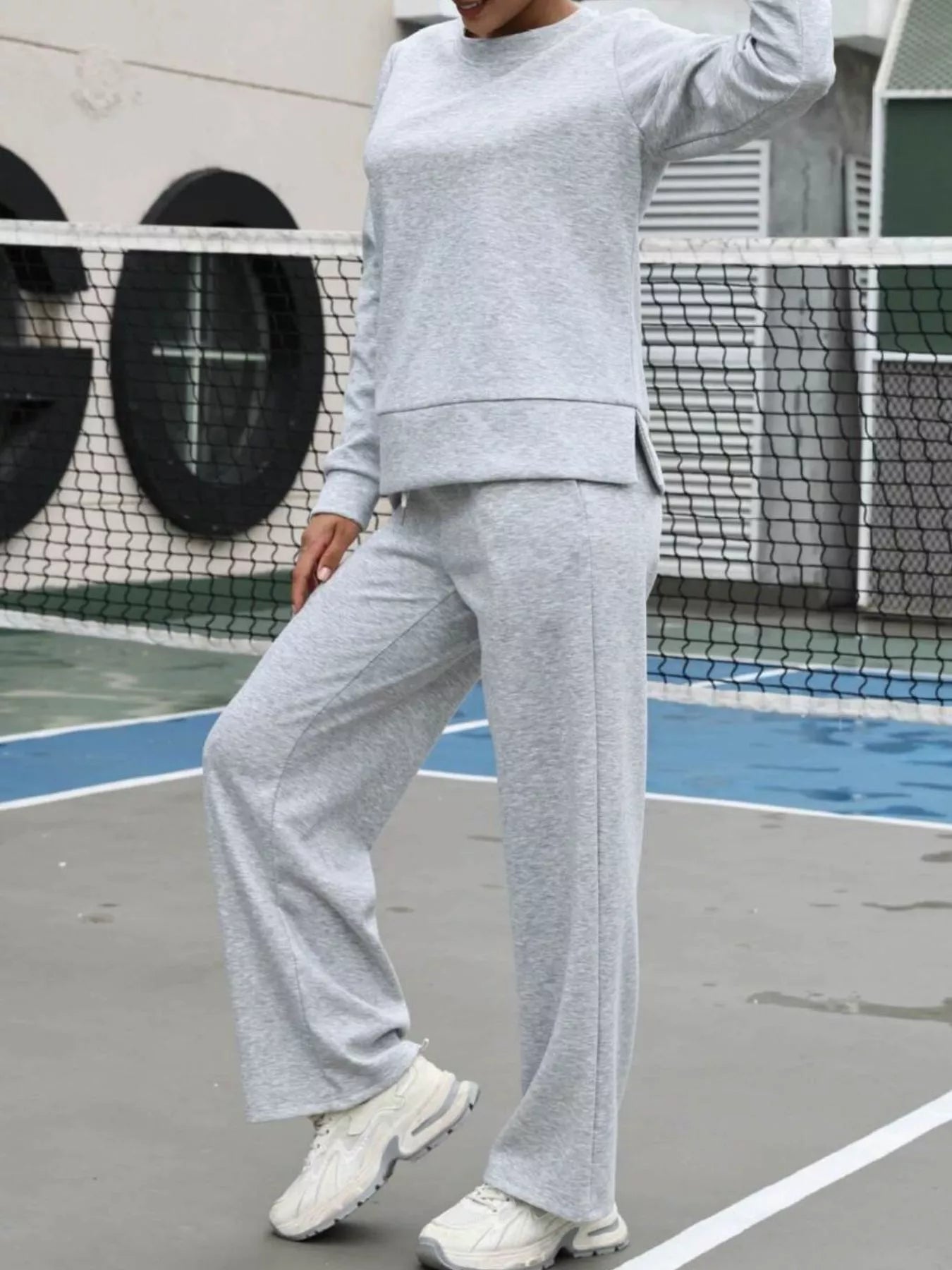 Person wearing a gray tracksuit on an outdoor court
