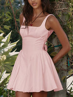 Woman wearing a pink dress standing in a natural setting with greenery.