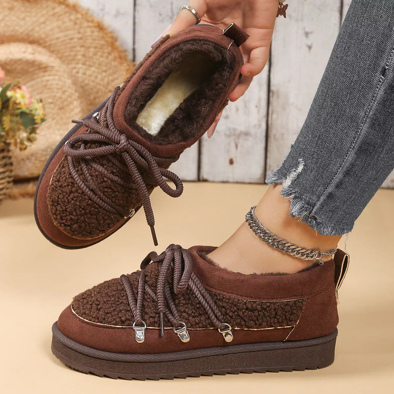 Brown fleece-lined shoes being worn with a wooden floor background