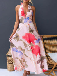 Woman wearing a floral dress sitting on a wicker chair against a dark gray wall.