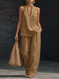Woman in beige outfit holding a woven bag against a dark background