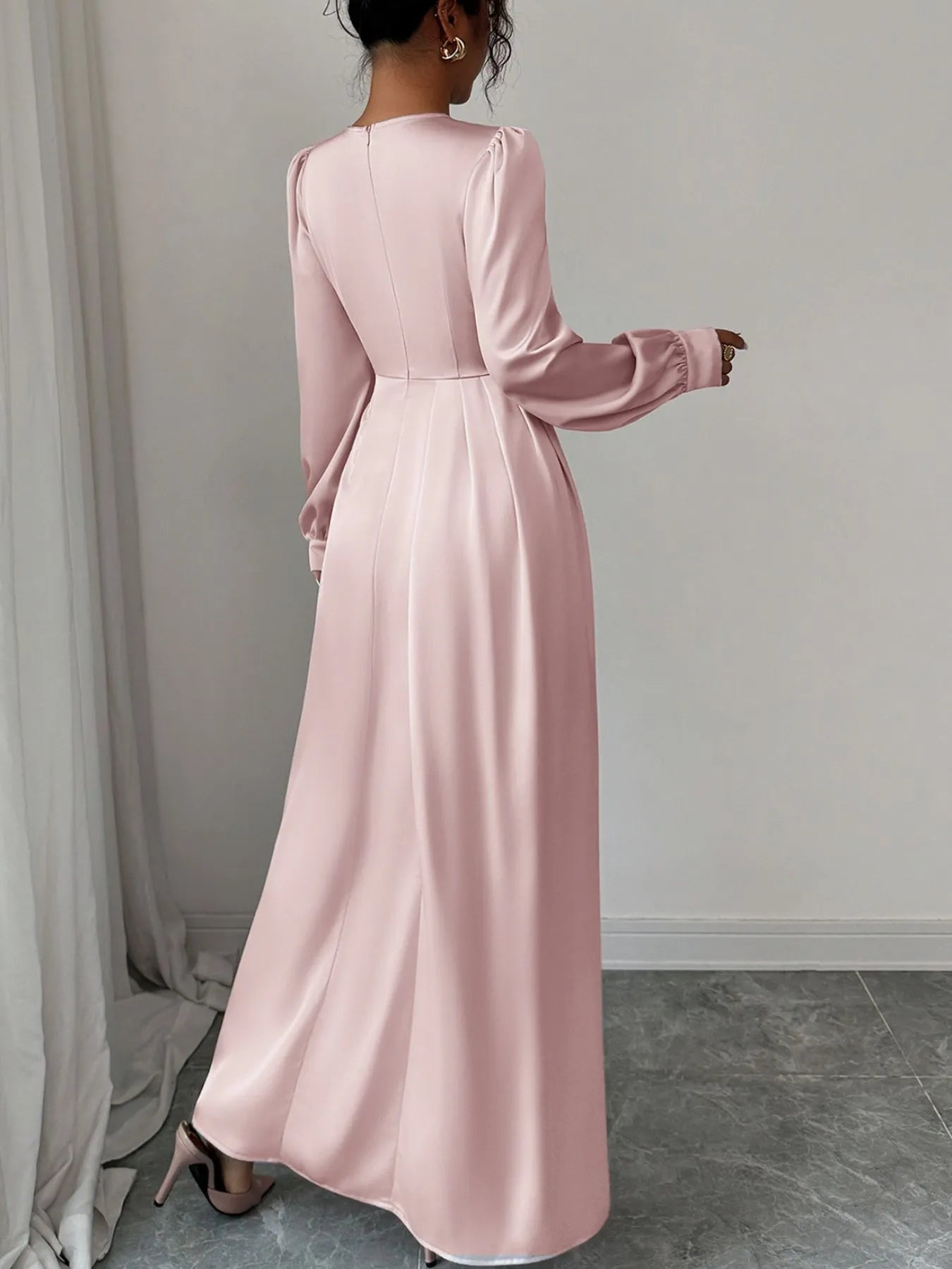 Woman wearing a pink long-sleeve dress against a plain background