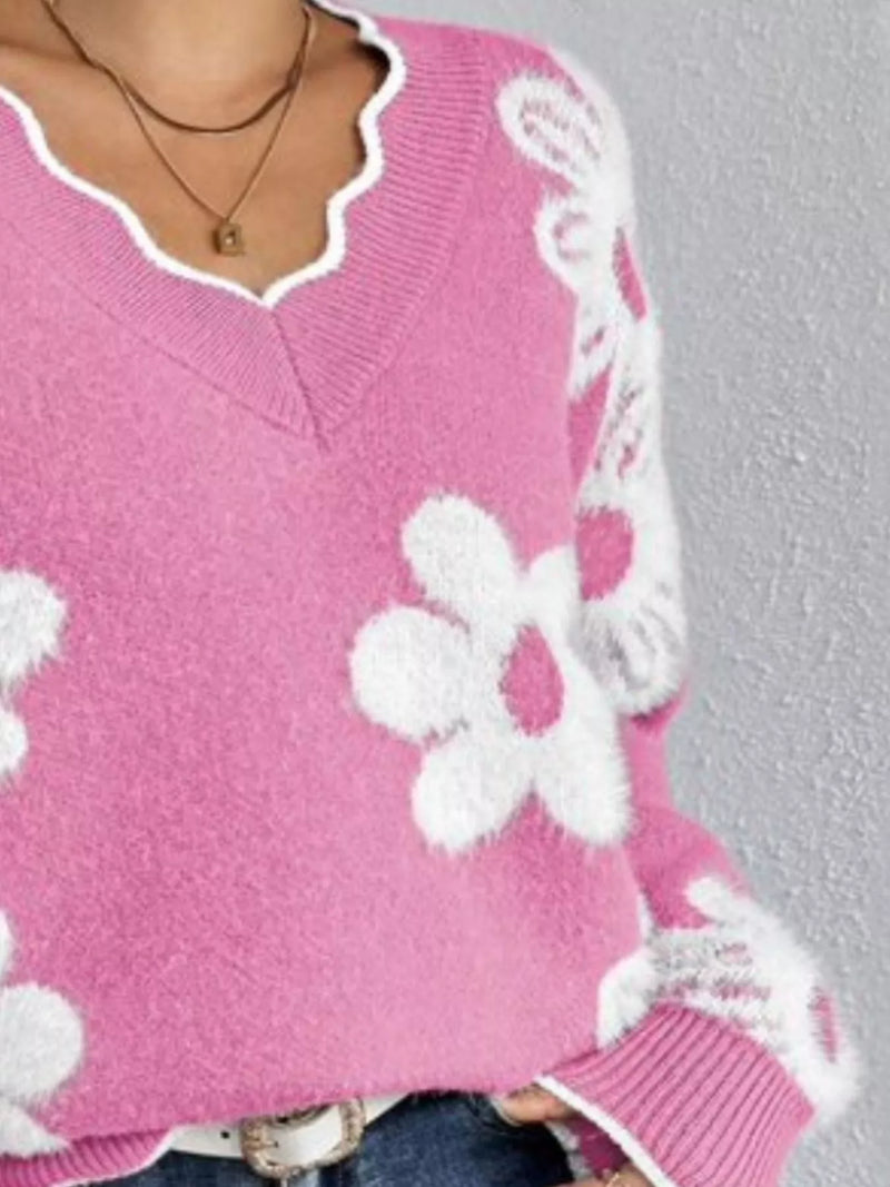 Pink sweater with white floral patterns on a gray background