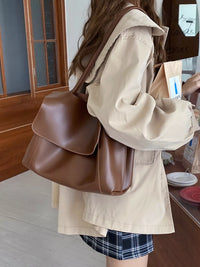 Person wearing a beige jacket with a brown leather bag