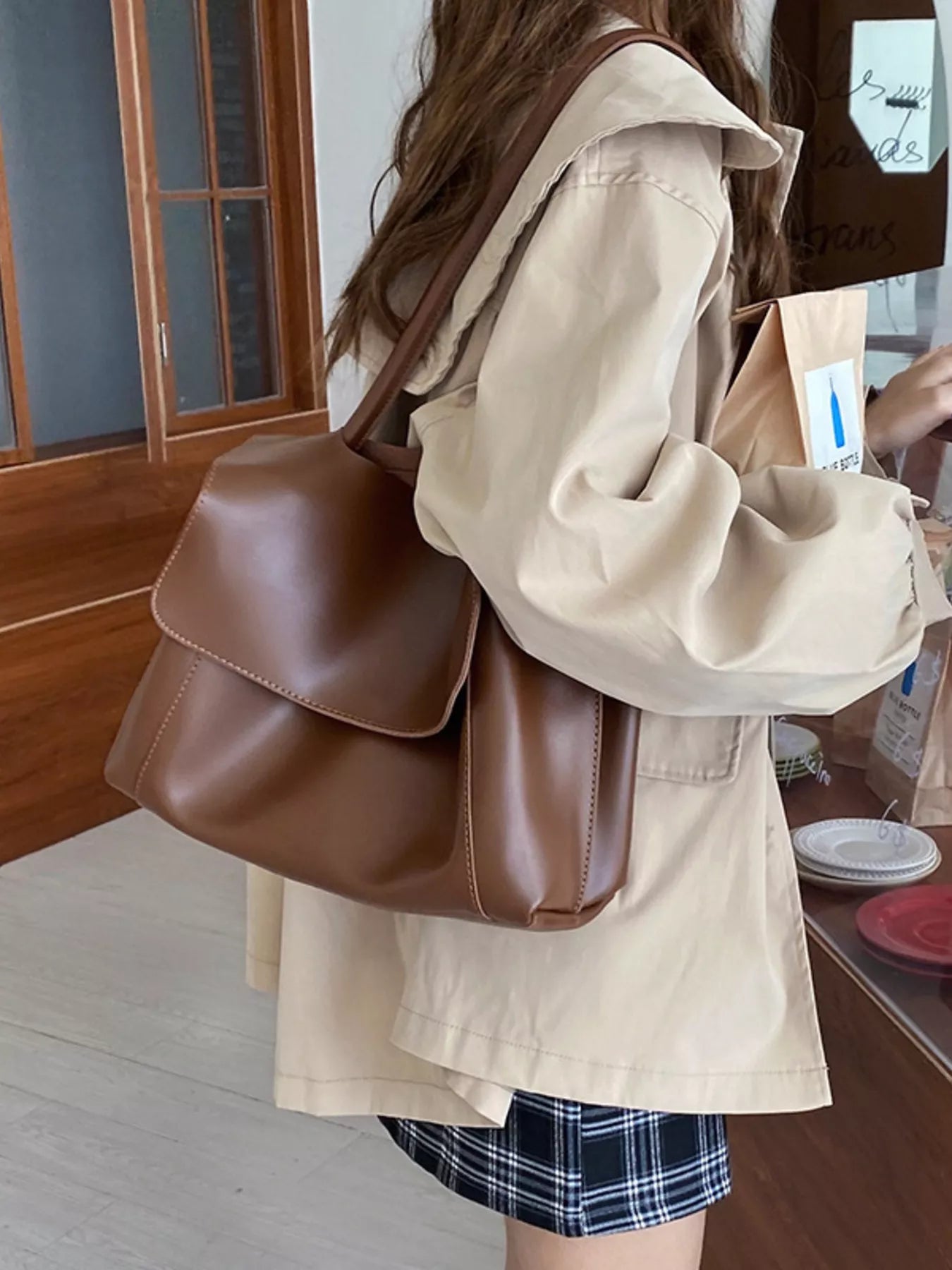 Person wearing a beige jacket with a brown leather bag