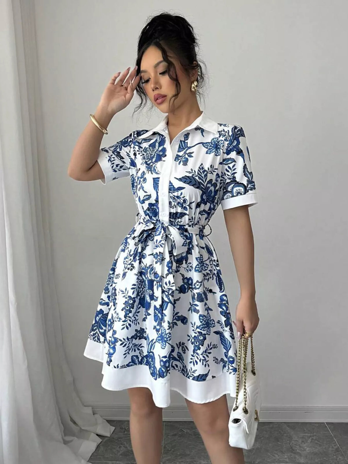 Woman wearing a blue and white floral dress against a plain background