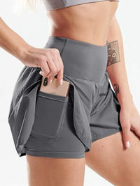 Person wearing gray athletic shorts with a pocket, holding a phone.