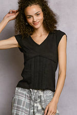 Woman wearing a black sleeveless top with plaid pants against a gray background