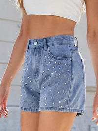 Denim shorts with stud embellishments worn by a person against a neutral background
