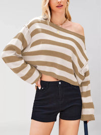Person wearing a striped sweater and black shorts on a plain background