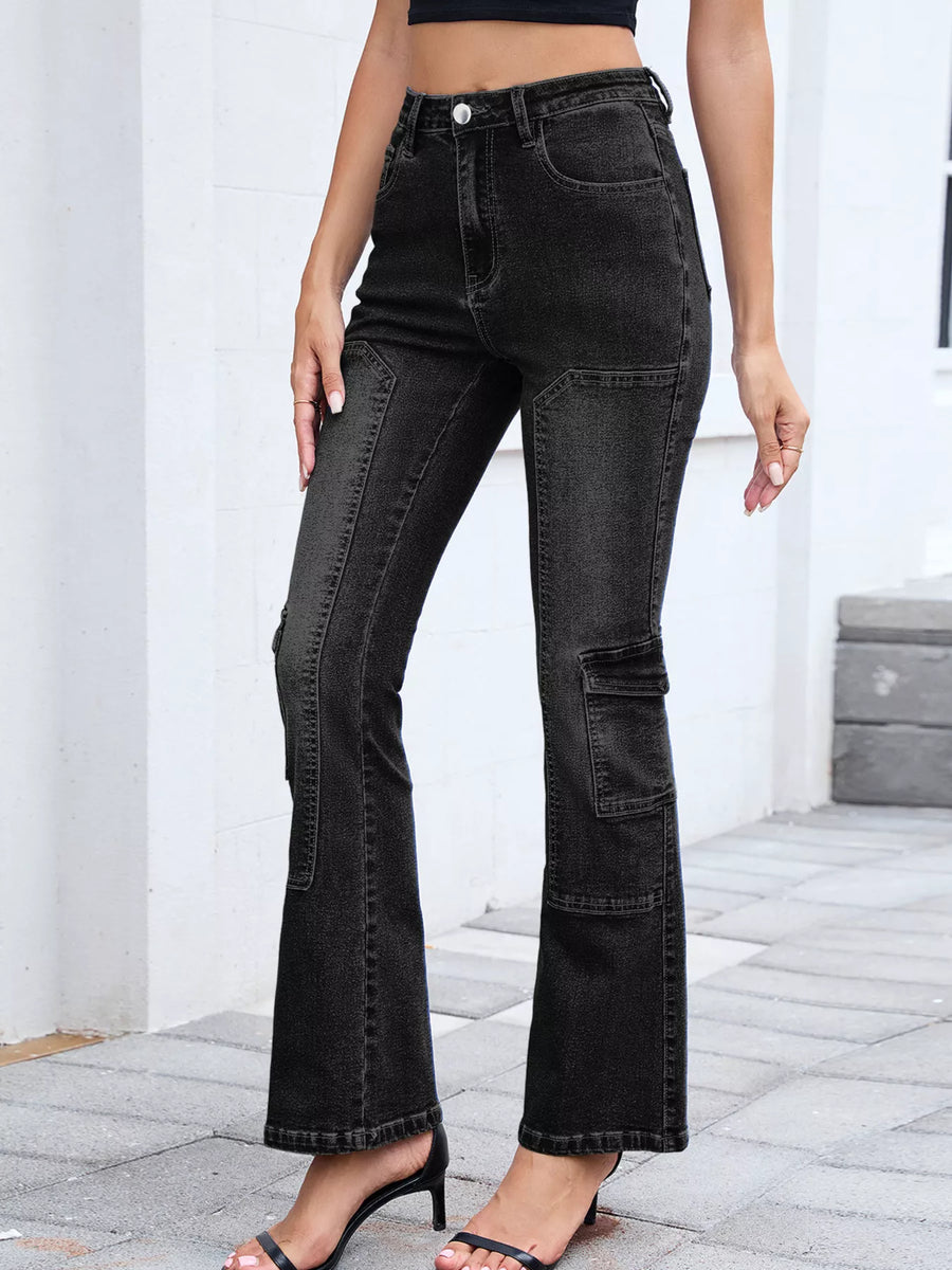 Person wearing black flared jeans standing on a stone floor with a white wall background