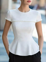 White blouse with pearl details worn by a person, blurred background
