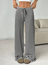 Person wearing black and white striped pants in a casual setting.