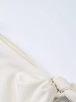 Close-up of a white fabric with a knot on a light gray background