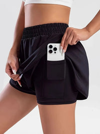 Person wearing black shorts with a pocket holding a phone on a white background