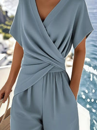 Light blue jumpsuit worn by a person with a blurred background of water and boats.