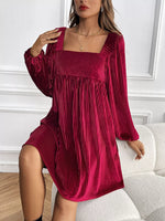 Woman wearing a burgundy pleated dress in an indoor setting