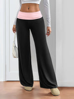 Person wearing black wide-leg pants with a pink waistband, standing indoors.