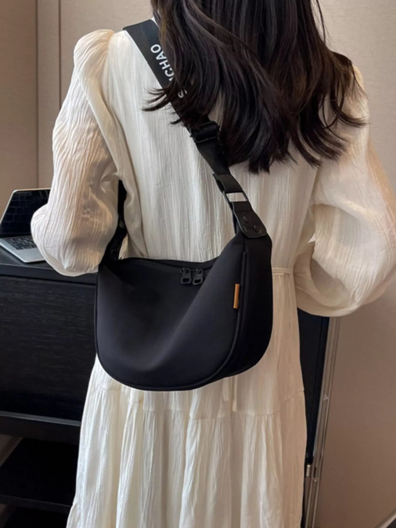 Person wearing a black crossbody bag with visible branding.