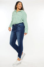 Person wearing a light green shirt and blue jeans on a white background