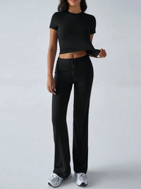 Person wearing a black crop top and black pants on a white background