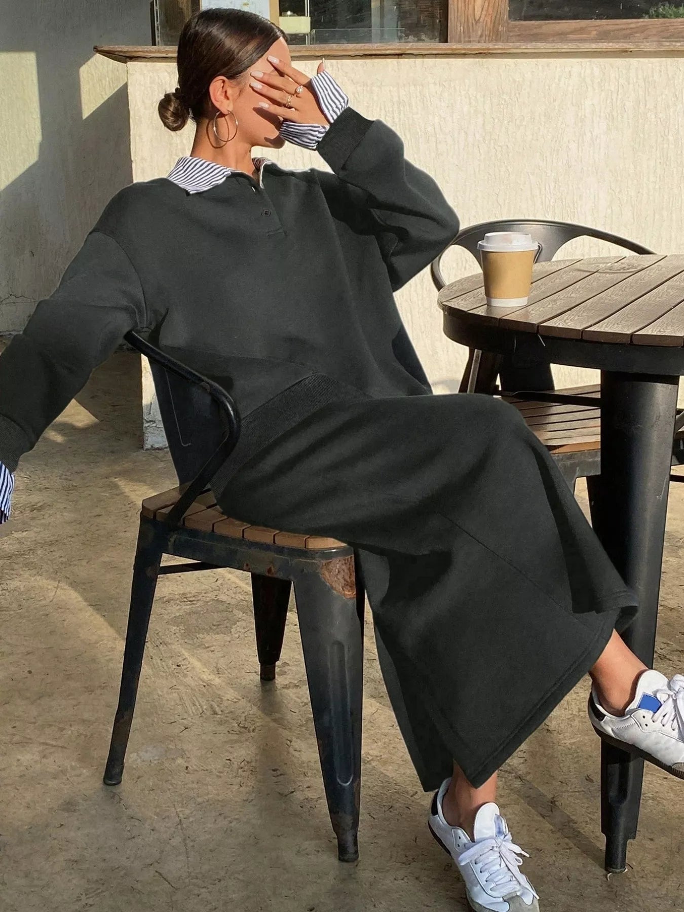 Person sitting outdoors with a coffee cup on a table