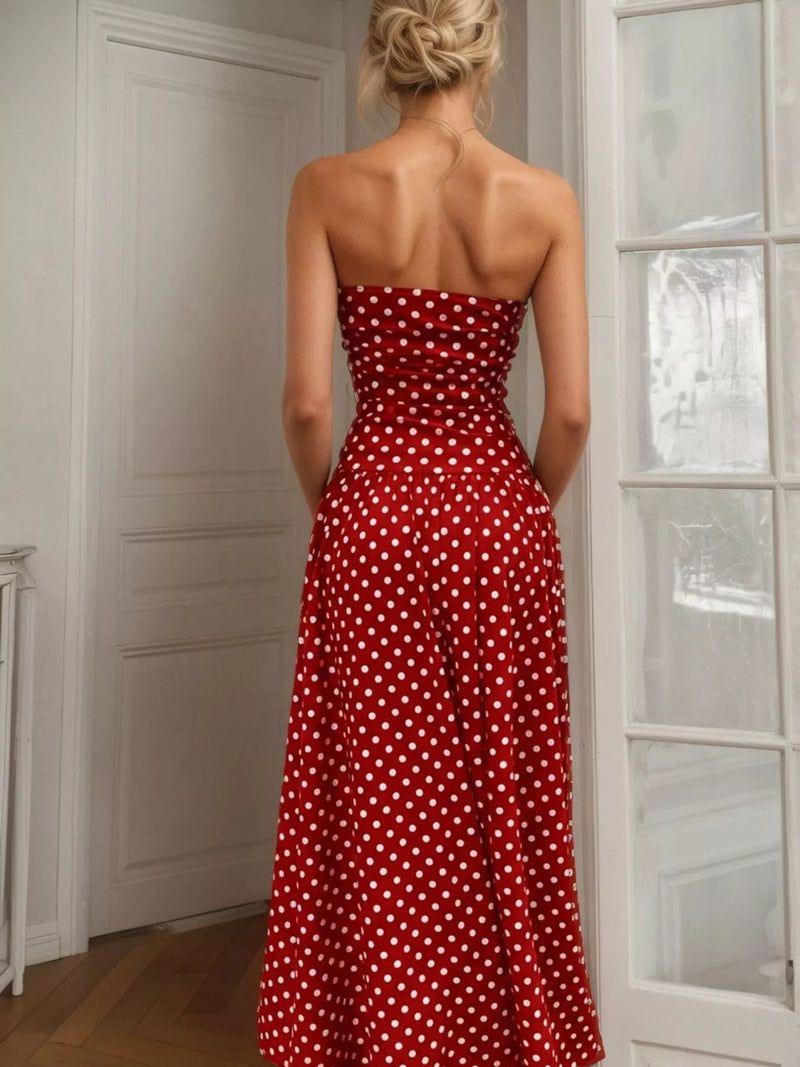 Woman wearing a red polka dot dress standing in a room with white walls and a glass door.