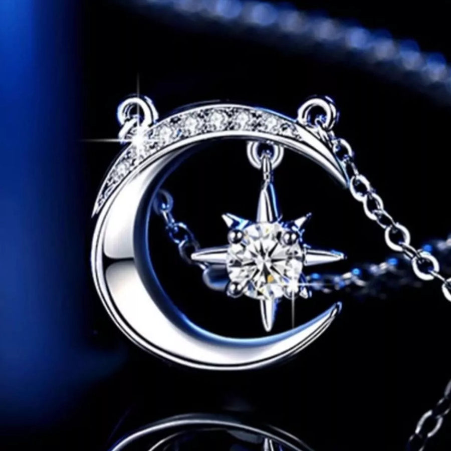 Silver necklace with moon and star pendant on a dark background