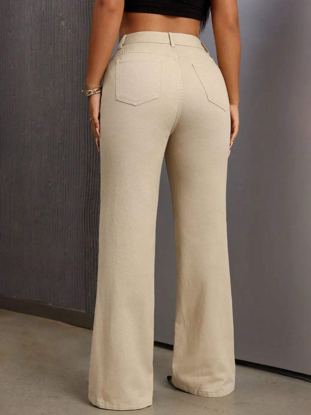 Person wearing beige flared pants against a gray background