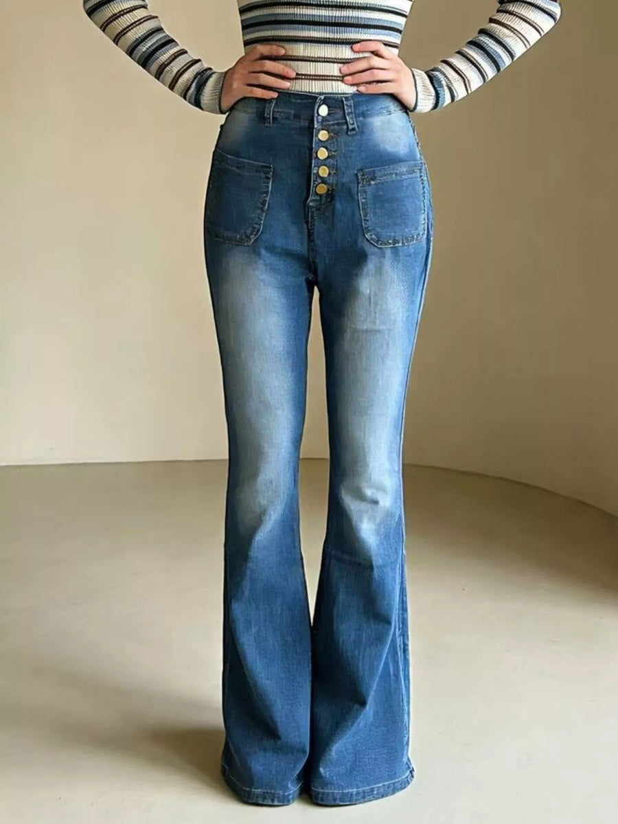 Person wearing a striped long-sleeve top and blue flared jeans on a neutral background