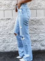 Person wearing light blue jeans with a brick wall background