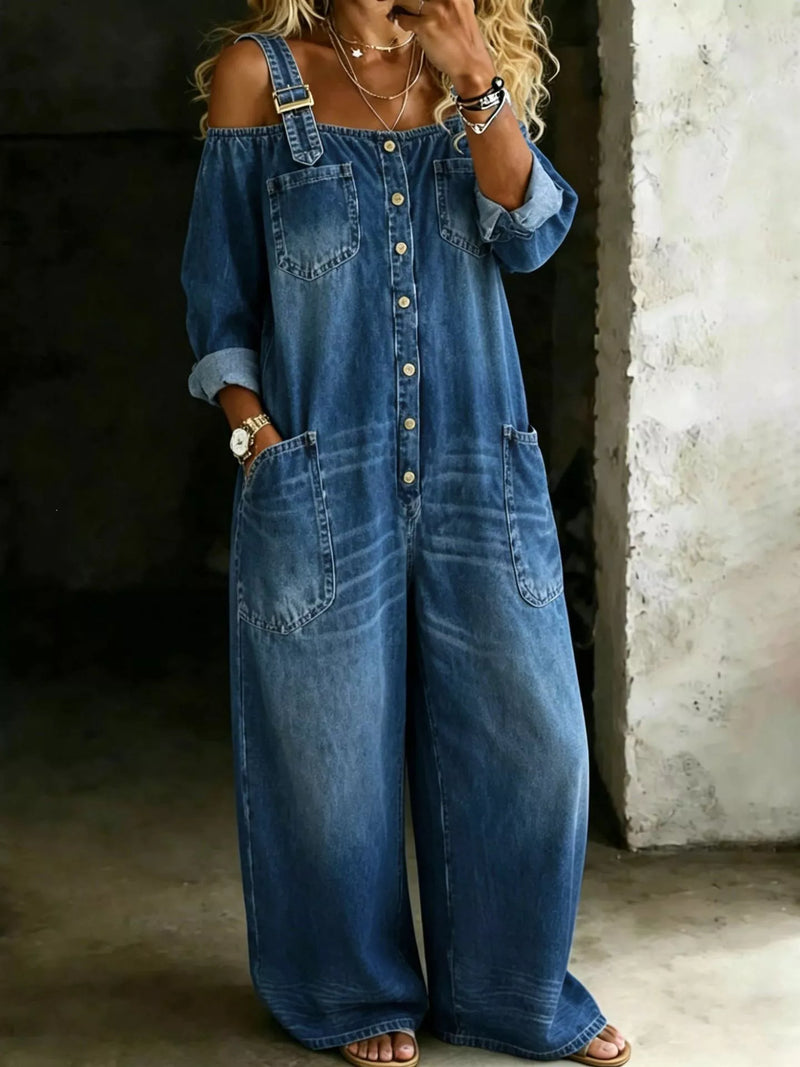 Person wearing a blue denim jumpsuit in a dimly lit room.