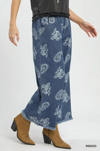 Blue denim pants with white paisley pattern worn by a person on a white background