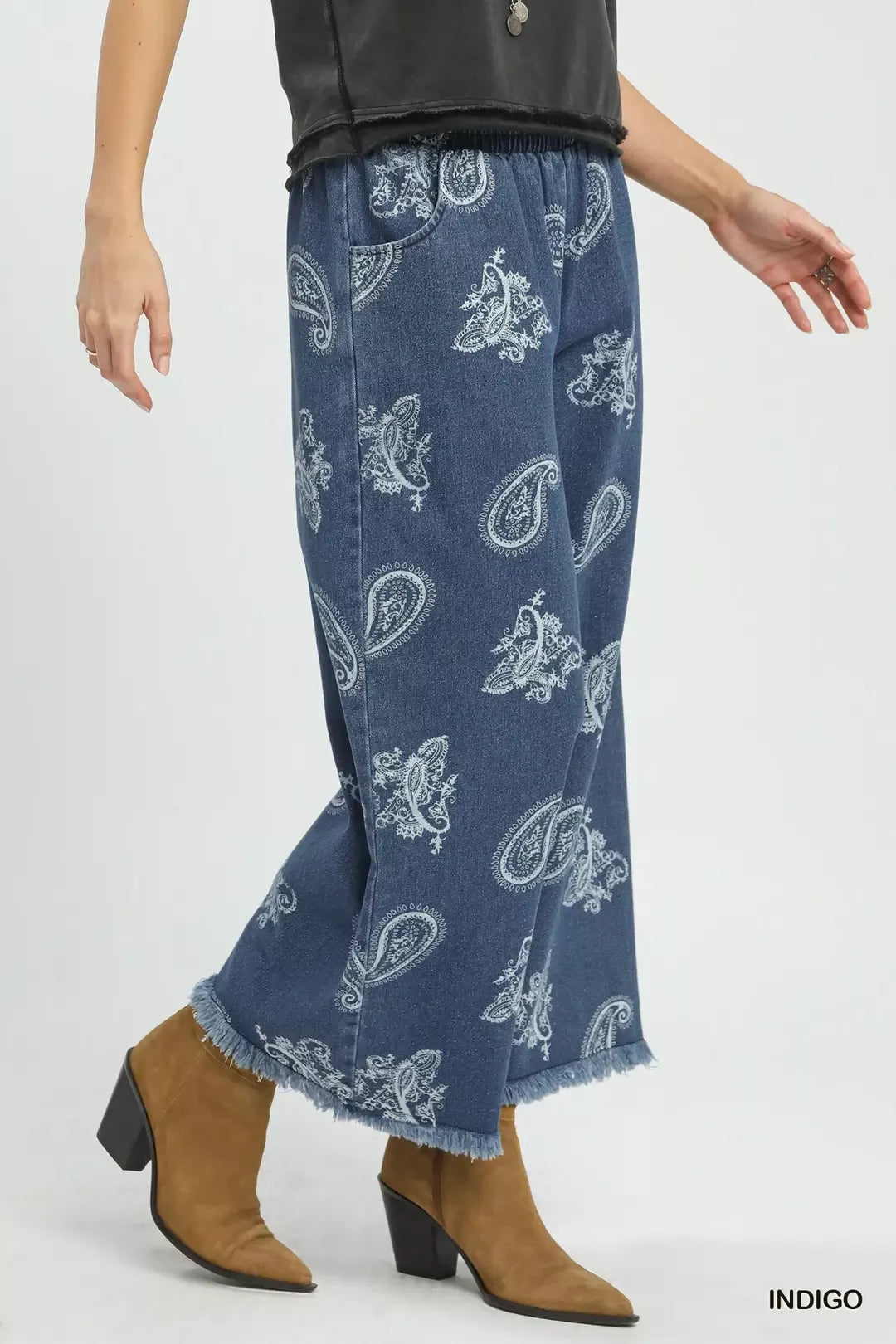 Blue denim pants with white paisley pattern worn by a person on a white background